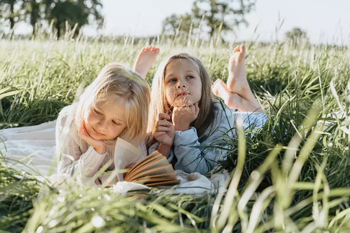Små flickor ligger på ett grönt gräsfält - Horoskop